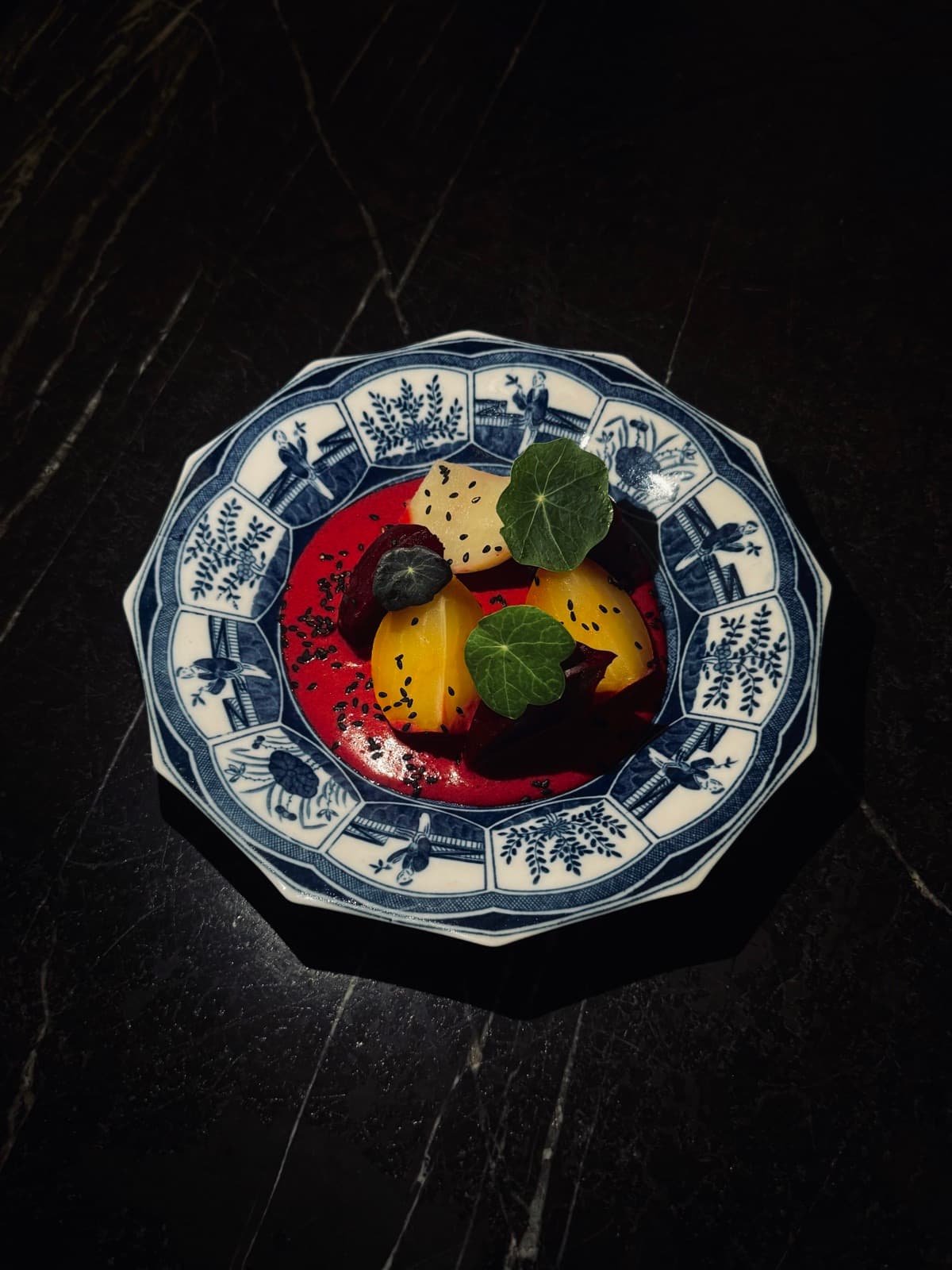 Gerecht met biet, perzik en Oost-Indische kers op een blauw-wit bord