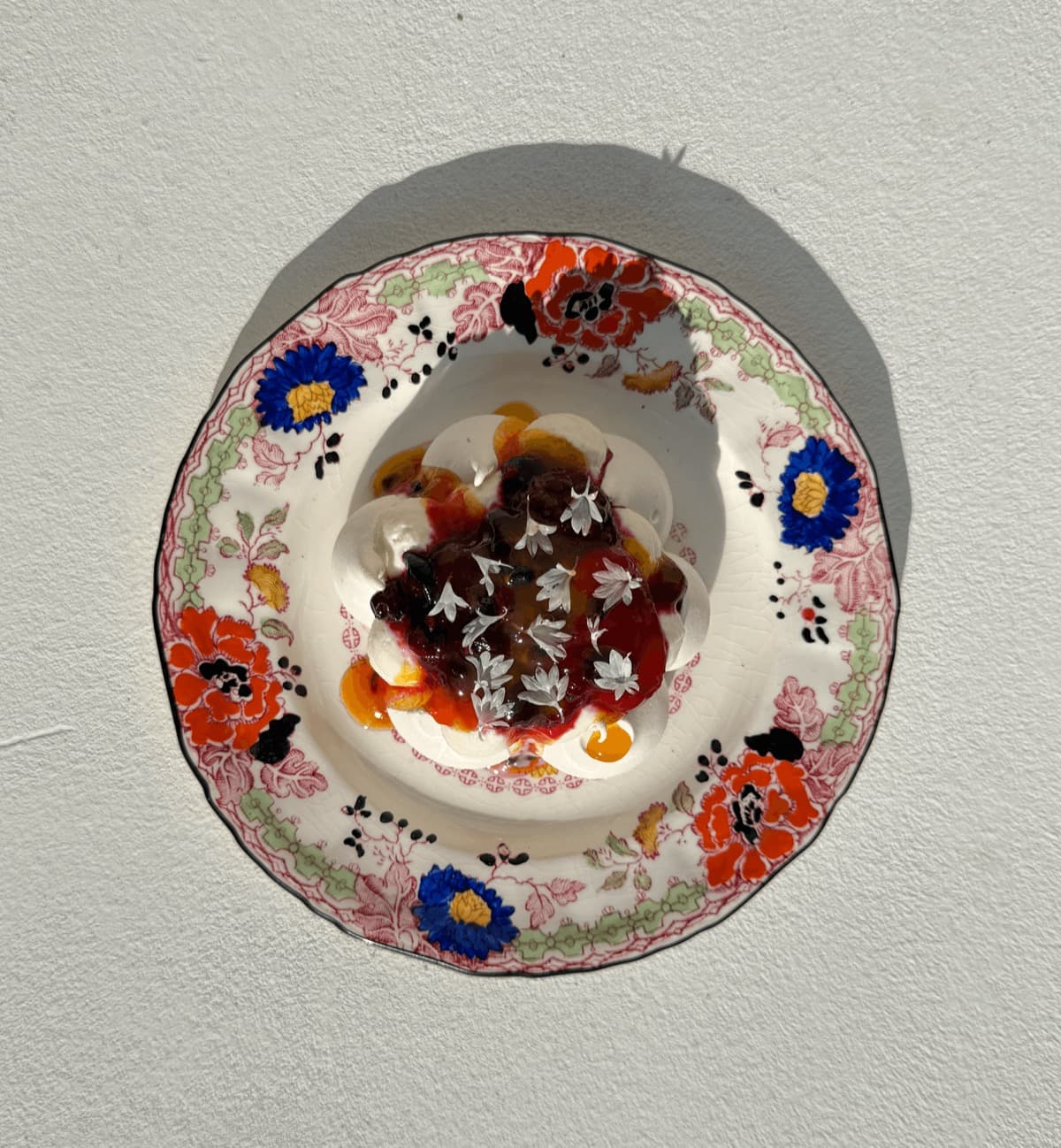 Gerecht met bloemen en fruit op een bord met bloemenrand, van bovenaf gezien